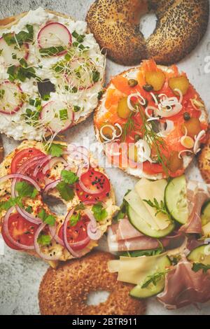 Hausgemachte Bagel-Sandwiches mit verschiedenen Belägen, Lachs, Hüttenkäse, Hummus, Schinken, Rettich Stockfoto