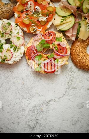 Hausgemachte Bagel-Sandwiches mit verschiedenen Belägen, Lachs, Hüttenkäse, Hummus, Schinken, Rettich Stockfoto