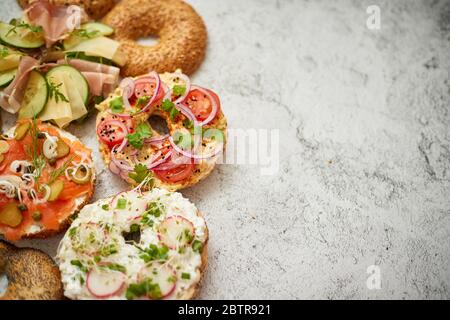 Hausgemachte Bagel-Sandwiches mit verschiedenen Belägen, Lachs, Hüttenkäse, Hummus, Schinken, Rettich Stockfoto