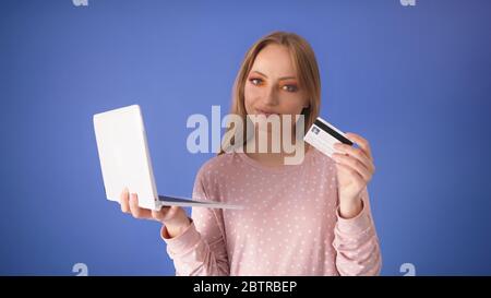 Junge kaukasische Frau mit großem Lächeln Laptop und Kreditkarte hält. Online-Shopping-Konzept. Stockfoto