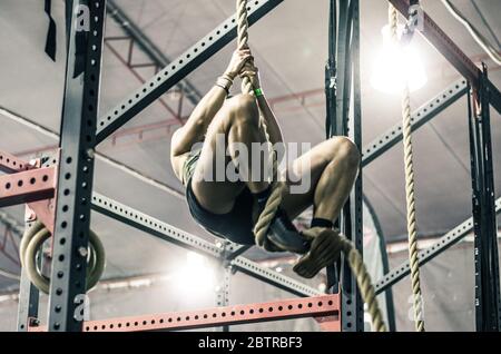 Nicht erkennbare Junge athletische Frau arbeiten und Klettern ein Seil in einer Turnhalle Stockfoto