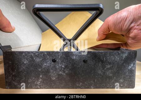 Ein Mann die Hand mit einem Kasten Datei Deckel öffnen und Feder Halter angehoben, ersetzen oder herausnehmen ein Dokument. Stockfoto