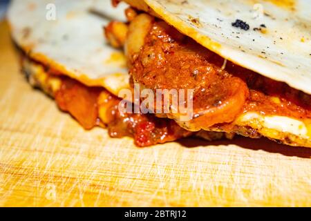 Quesadilla mit Hackfleisch, Wurst, roten Bohnen, Mais, Zwiebeln und Tomatensauce. Ein traditionelles mexikanisches Essen. Nahaufnahme Stockfoto