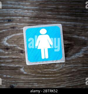 Ein blaues Damen-Toilettenschild, Symbol oder Symbol auf einem Holzblock mit Holzhintergrund und Kopierraum Stockfoto