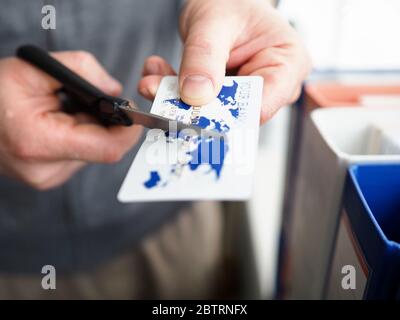 Männliche Hand schneiden Bankkarte mit Schere Stockfoto