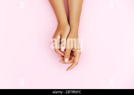 Zarte Hände mit perfekter blauer und rosafarbener Maniküre auf trendigen pastellrosa Hintergrund. Platz für Text. Stockfoto