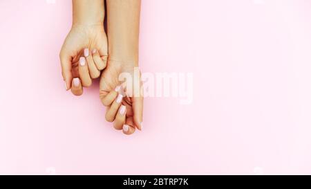 Zarte Hände mit perfekter blauer und rosafarbener Maniküre auf trendigen pastellrosa Hintergrund. Platz für Text. Stockfoto
