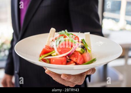 Mann hält griechischen Salat im Restaurant Stockfoto