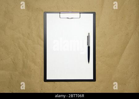 Ein Tablett mit einem weißen Blatt im A4-Format mit Stift auf einem beigen Bastelpapier. Konzept der Analyse, des Studiums, der aufmerksamen Arbeit. Stock Foto mit leerem Platz für Ihren Text und Design. Stockfoto