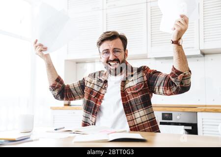 Porträt des jungen bärtigen unzufrieden Mann trägt Brille arbeiten mit Notizen zu Hause Stockfoto