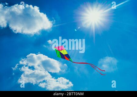 Bunte Spielzeugdrachen gegen blauen bewölkten Himmel an einem sonnigen Tag Stockfoto