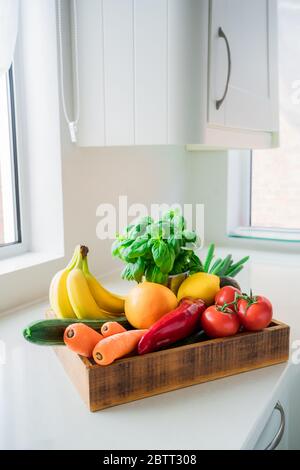 Frisches Bio-Gemüse, Obst und Grün in einer Holzkiste auf weißem Küchentisch. Lokale Bauern gesunde Ernährung. Keine Abfälle und plastikfreie Lebenswirklichkeit Stockfoto