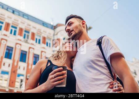 Gemischtes Rennpaar in der Liebe zu Fuß in der Stadt. Arabischer Mann und weiße Frau trinken Kaffee Umarmung im Freien Stockfoto