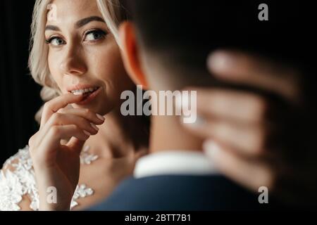 Blonde Braut, die ihre Hand um den Hals des Bräutigams hält Stockfoto