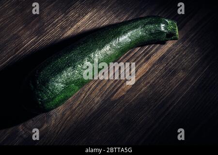 Zucchini auf einem dunklen Holz rustikalen Tisch, gesundes Essen Konzept, dunkle Lebensmittel Bild Stockfoto