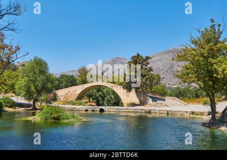 Römische Brücke insel kreta im preveli Tal hinter einem blauen Teich, Berge im Hintergrund Stockfoto