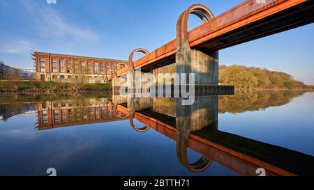 Die Orange Brücke zur alten Spinnerei spiegelt sich im Neckar, ein Gerüst ist zu sehen. Plochingen, Deutschland Stockfoto