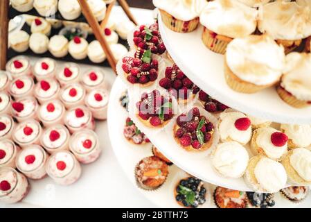 Köstliche Mini-Kuchen in Büfetts. Mit Himbeeren dekorierte Cupcakes. Verschiedene Desserts auf Party. Feier, Party, Geburtstag oder Hochzeit Konzept. Stockfoto