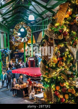 BOROUGH MARKET WEIHNACHTEN erhöhten Blick auf den späten Abend Käse Marktstände und Verkostung Proben, mit produzieren themenbezogene Weihnachten Kranz hängen in den Vordergrund Borough Market Southwark London SE1 Stockfoto