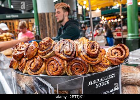 Borough Market Bakery Specialty Brot Lebensmittel Allergie Hinweis. Borough Market Bakery ‘Bread ahead’ Stand mit einer Vielzahl von attraktiven handgefertigten Broten zum Verkauf mit süßen Zimt-Brötchen im Vordergrund. Lebensmittel Allergie Hinweis in voller Ansicht platziert. Handwerkliche Bäckerei-Spezialität am Borough Market Southwark London, Großbritannien Stockfoto