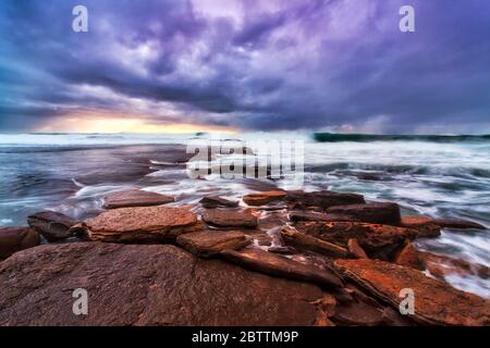 Flache erodierte Sandsteinfelsen der Sydney Northern Beaches bei Sonnenaufgang. Stockfoto