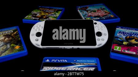 PlayStation Vita Handheld-Konsole in Glacier White umgeben von Spielen auf schwarzem Hintergrund. Stockfoto