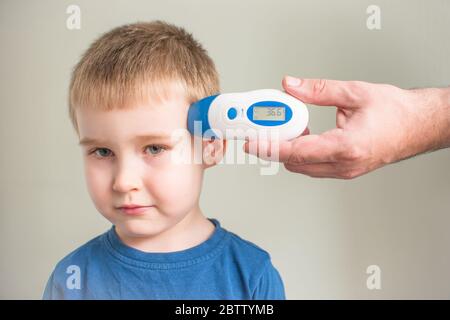 Mann überprüft Jungen Körpertemperatur mit einem digitalen Thermometer für Virus covid-19 Symptom - epidemische Ausbruch Konzept. Coronavirus stoppen Stockfoto