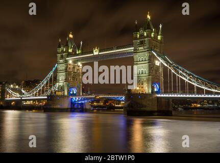 Die Tower Bridge in London leuchtete nachts auf, und die glatte Themse lief darunter. Stockfoto