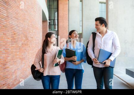 Drei asiatische Studenten gehen in der Universitätshalle während der Pause an der Universität zu Fuß und reden zusammen. Bildung, Lernen, Student, Campus, Universität, Stockfoto