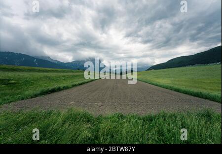 Frisch gepflanzte Gemüsefarm im Bergtal in den österreichischen Alpen mit Sturmwolkenlandschaft, Mieminger Plateau, Tirol, Österreich Stockfoto