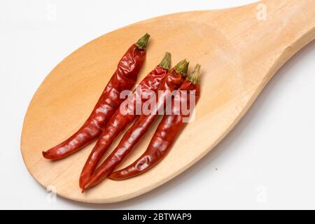 Nahaufnahme der roten Chili in einem Holzlöffel auf weißem Hintergrund. Stockfoto