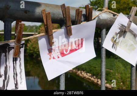 Wernau, Deutschland - 24. April 2020: Handbemalte Papiernotizen mit dem Wort Mut in Wernau am Neckar. Befestigt an einem Geländer einer Brücke mit Wäscheständer Stockfoto