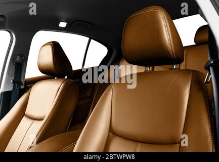 Interieur aus braunem Leder des Luxuswagens. Teil von Leder Autositz Details mit Nähten. Bequeme, perforierte Ledersitze in Orange. Braune perforierte Leine Stockfoto