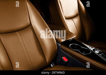 Interieur aus braunem Leder des Luxuswagens. Teil von Leder Autositz Details mit Nähten. Bequeme, perforierte Ledersitze in Orange. Braune perforierte Leine Stockfoto