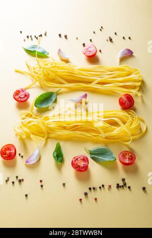 Hausgemachte Pasta und Kirschtomaten auf gelber Oberfläche Stockfoto