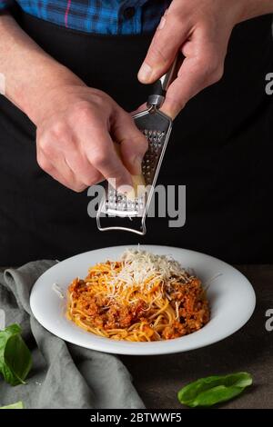 Bolognese Pasta. Männer geben Käse auf Spaghetti Stockfoto