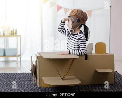 Asiatische kleine Kind Mädchen spielen mit Karton Spielzeug Flugzeug Handwerk in Hause mit Kopierraum für Ihren Text isoliert, Kreativ mit Familie und dreami Stockfoto