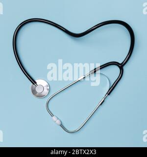 Stethoskop in Form von Herz auf blauem Tischhintergrund, gute Gesundheit von Doktor Konzept, Draufsicht mit isoliert auf blau Stockfoto