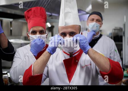 Gemischtes Rennteam Porträt von Gruppenköchen, die zusammen in der Küche im Restaurant mit medizinischer Schutzmaske und Handschuhen in Coronavirus New n Stockfoto