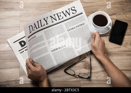 Hände, die die Wirtschaftszeitung auf Holztisch halten, Daily Newspaper Mock-up Konzept Stockfoto