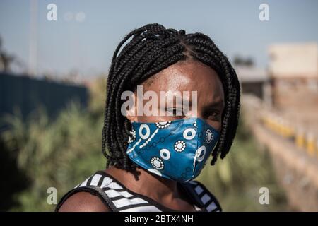 Frau, die eine lokale handgefertigte Gesichtsmaske aus traditionellem afrikanischen Stoff zum Schutz vor Corona-Virus trägt Stockfoto