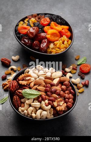 Verschiedene getrocknete Früchte und Nüsse auf einem dunklen Steintisch Stockfoto