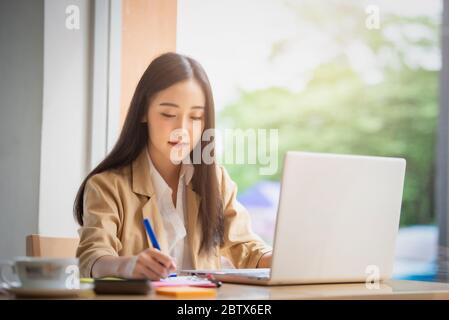 Porträt der jungen asiatischen Geschäftsfrau sitzt drinnen im Café mit digitalen Tablet mit Kaffee. Business Success Concept. Stockfoto