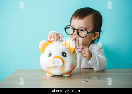 Niedliches kaukasisches Baby, das mit Sparschwein spielt Stockfoto