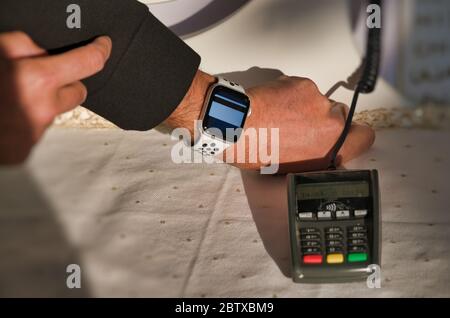 Kontaktlose Zahlung. Mann nähert Smartwatch zu tragbaren Maschine in einem Geschäft. Stockfoto