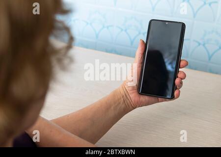 Oma ist am Telefon. Ein älterer Mann schaut auf einen leeren Telefonbildschirm. Ein leerer Bildschirm für den Test und das Design. Alte Frau mit Brille hält ein Stockfoto