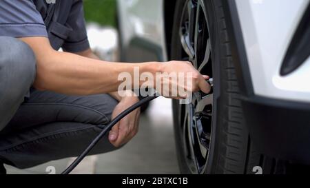 Mann füllt Luft in die Reifen seines Autos (aufblasender Reifen) Stockfoto