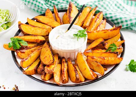 Gebackene Kartoffeln mit geräuchertem Paprika und Sauce auf hellem Hintergrund. Stockfoto