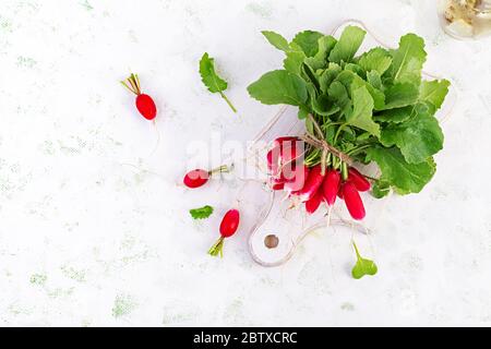 Frühling Ernte roten Rettich auf hellem Hintergrund. Ein paar frische französische Rettich zum Frühstück. Gemüse anbauen. Vegetarisches Essen. Draufsicht, flaches Lay Stockfoto