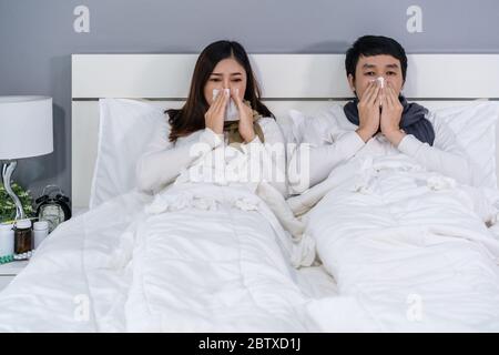 Kranke Paar niesen und leiden an Viruserkrankungen und Fieber auf dem Bett zu Hause Stockfoto